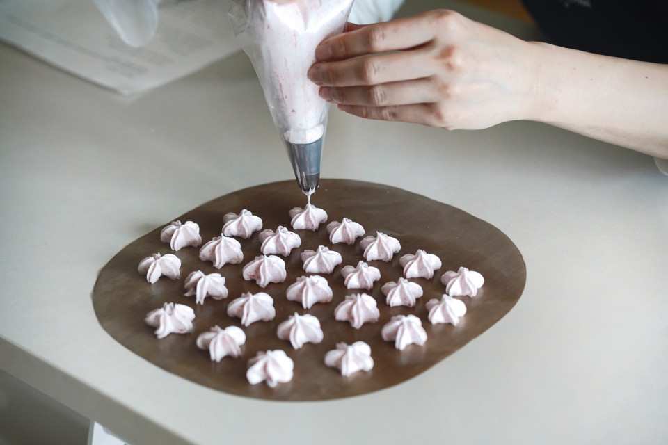 把步驟3的蛋白霜裝入擠花袋，裝上櫻花花嘴，將蛋白霜適量擠至烘焙紙上。